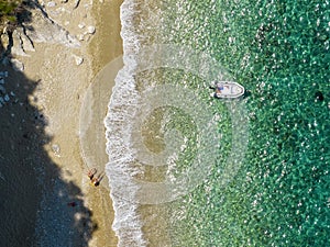 Aerial view of a moored dinghy floating on a transparent sea. Coastline, Corfu, Greece