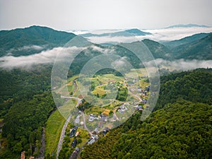 Aerial view of morning fog over remote village in forested mountains