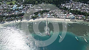 Aerial view of motor boats docked on Run Island with stilt houses at the back on wooden deck. bright blue sky.. Maluku, Indonesia