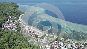 Aerial view of motor boats docked on Run Island with stilt houses at the back on wooden deck. bright blue sky.. Maluku, Indonesia