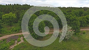 Aerial view on motorcyclist on a winding rural road through a scenic lush green forested mountain valley