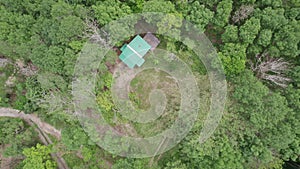 Aerial view of mountain hillside with small hut in the forest