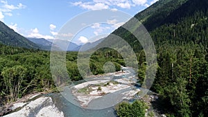 Aerial view: mountain river flows through green forest. Caucasus mountains, river and wild forest