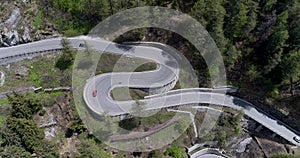 Aerial view of mountain serpentine road with trucks and cars driving on zig zag go up and down in Europe Switzerland 4K