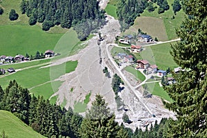 Aerial view of mountain stream in the Austrian Alps blocked after a massive mudflow with excavator and truck working to clean up
