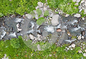 Aerial view mountain stream with colourful stones. Flowing river with smooth stones. Spring water running through different stones