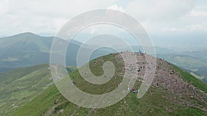 Aerial view of the mountain top with many young hikers against the backdrop of a mountain landscape.