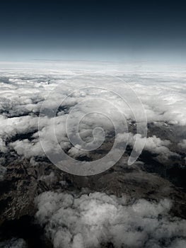 Aerial view on the mountains from the airplane window. Cloudy day. Background picture.