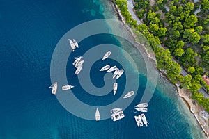 Aerial view of a much chaotically standing boats in a bay at sunset, Croatia, coastline with azure water and green trees