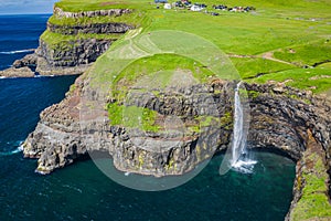 Aerial view of Mulafossur waterfall in Gasadalur village in Faroe Islands, North Atlantic Ocean. Photo made by drone from above.