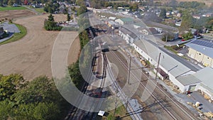 Aerial view of multiple antique restored steam engines in a train yard steaming up blowing smoke