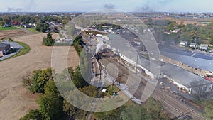 Aerial view of multiple antique restored steam engines in a train yard steaming up blowing smoke