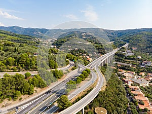 Aerial view of multiple lane highway crossing villages and forest hills Autostrada dei Fiori - A10 Liguria Italy