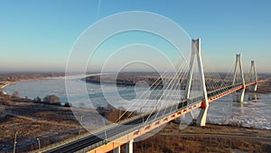 Aerial view of multispan cable-stayed Murom Bridge across ice covered Oka river on sunny winter day, Vladimir region
