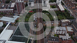 Aerial view of multitrack railway line in urban borough. Tilt down and tracking passenger train. London, UK