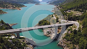 Aerial view of natural landscape with the bridge linking two mountain slopes above sea strait. Clip. Amazing turquoise