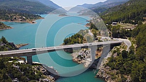 Aerial view of natural landscape with the bridge linking two mountain slopes above sea strait. Clip. Amazing turquoise