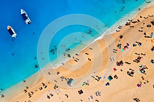 Aerial view of Navagio beach, Zakynthos Island, Greece. People relaxing on the beach during their vacation. Blue sea water. A boat