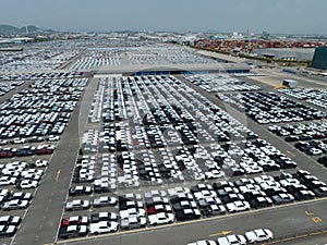 Aerial view of new cars stock at factory parking lot. Above view cars parked in a row. Automotive industry. Logistics business.