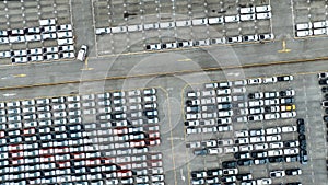 Aerial view of new cars stock at factory parking lot. Above view cars parked in a row. Automotive industry. Logistics business.