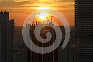 Aerial view of new developing residense in american urban area at sunset. Tower cranes at industrial construction site photo