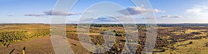 An aerial view of the New Forest with heartland, trees at golden hour under a majestic blue sky and white clouds