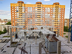 Aerial view of a new modern house under construction with a working people and equipment on the roof on the background