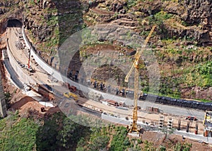 aerial view of a new road under construction with crane and construction materials and machinery working on the site with a tunnel