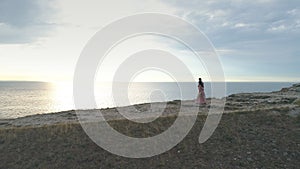 Aerial view on newlyweds go holding hands and laughing, against the background of rocks and green glade.