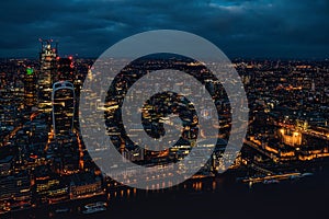 Aerial view of north London, blue hour just after sunset. Famous Tower visible in bottom right corner near river Thames. Orange