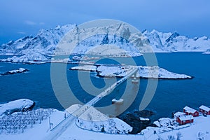 Aerial view of Norwegian fishing village in Reine City, Lofoten islands, Nordland, Norway, Europe. White snowy mountain hills,