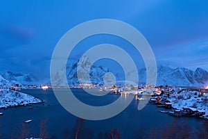 Aerial view of Norwegian fishing village in Reine City, Lofoten islands, Nordland, Norway, Europe. White snowy mountain hills,