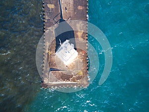 Aerial view of an observation white tower on a metal pier in the middle of turquoise sea water