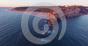 Aerial view of ocean, north Beach and Nazare lighthouse at sunset, Portugal