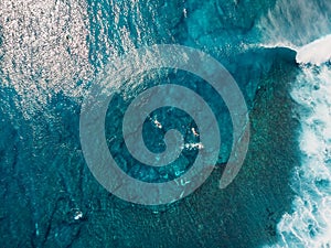 Aerial view of ocean water, waves and surfers at Bali island. Top view