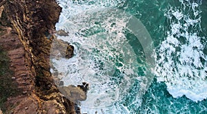 Aerial view of ocean waves crashing on rocks in Nazare, Portugal