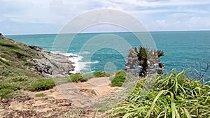 Aerial view of ocean waves hitting rocky cliffs in the blue ocean. Top view of coastal rocks in Phuket ocean. Landscape view point