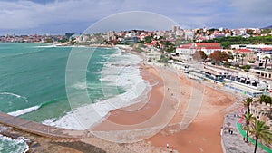 Aerial view: ocean waves splashing restlessly along the coast. Estoril beach. Portugal. Fly over drone shot. 4K
