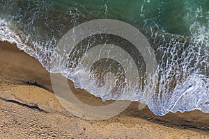 Aerial view of ocean waves washing a sandy shoreline