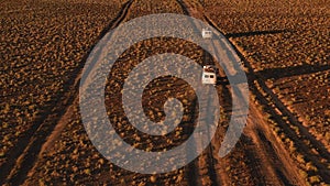 Aerial view off road 4x4 car driving along dirt road among the desert. Beautiful wild road in the desert at sunset. Road