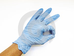 Aerial view of okay symbol with hand with blue latex disposable surgical glove isolated on white background. Protection against