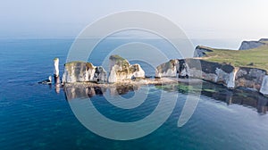 An aerial view of the Old Harry Rocks along the Jurassic coast with crystal clear water and white cliffs under a hazy sky