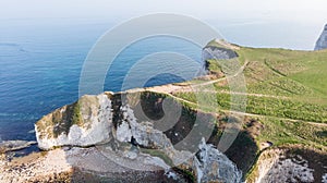 An aerial view of the Old Harry Rocks along the Jurassic coast with crystal clear water and white cliffs under a hazy sky