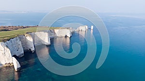 An aerial view of the Old Harry Rocks along the Jurassic coast with crystal clear water and white cliffs under a hazy sky