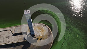 Aerial view of the old lighthouse by the green muddy flowered water