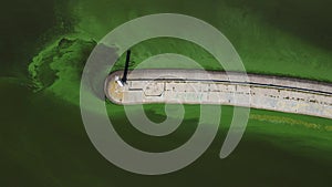 Aerial view of the old lighthouse by the green muddy flowered water