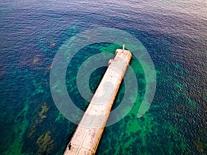 Aerial view of old pier and small lighthouse above water on Cascais-Estoril coast in Portugal