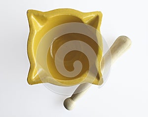 Aerial view of old yellow ceramic mortar, empty and with wooden pestle. Yellow mortar to make a sauce called Allioli, typical of