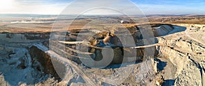 Aerial view of open pit mine of sandstone materials for construction industry with excavators and dump trucks. Heavy