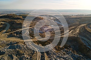 Aerial view of open pit mine of sandstone materials for construction industry with excavators and dump trucks. Heavy